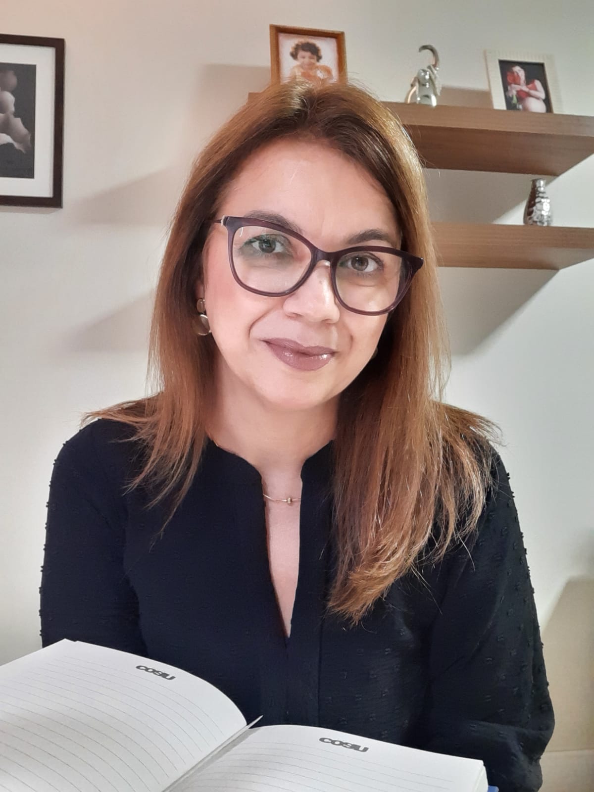 Katia Reis sorrindo, com um caderno aberto nas mãos